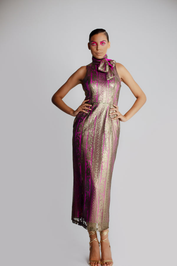 Model in gold lace sheath dress with bow and neck and v-back